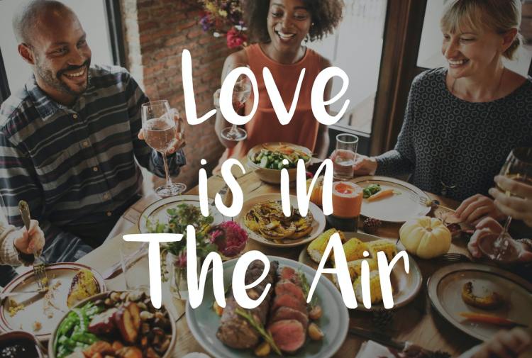 Family gathered around a table with wine and several food dishes as if celebrating in the fall.
