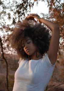 Pretty African American woman with natural afro stretching her arms overhead. 